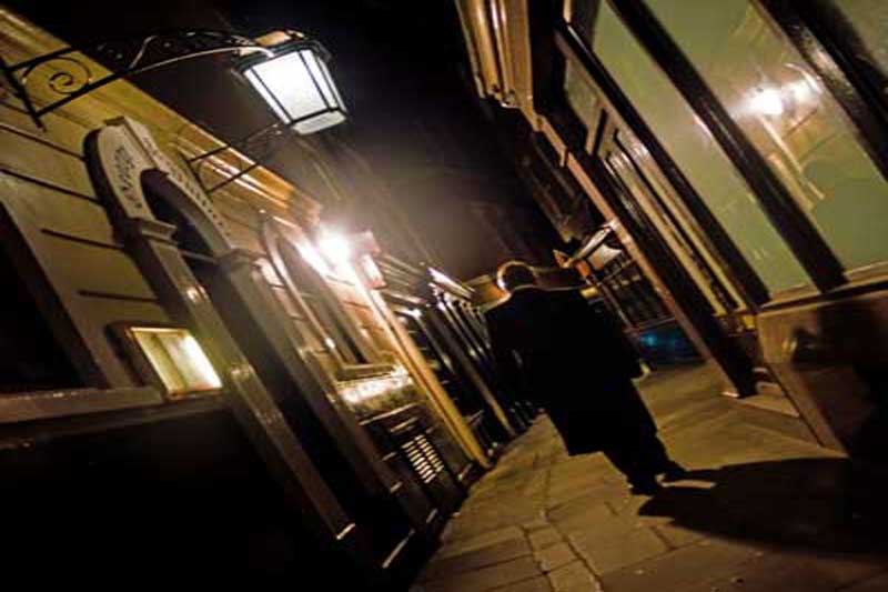 A ghost walk guide walking through an alley.