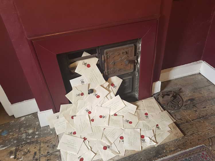 Letters pouring out of a fire place at the House of Minalima.